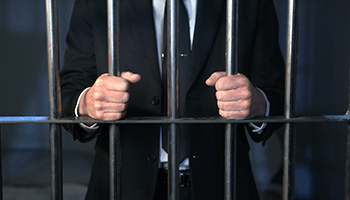 a photo of a man in a suit behind the bars, representation of federal crimes